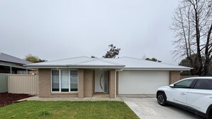 A residential house with a garage, a driveway, and a lawn. - Wagga Apartments #10 (Wagga Wagga)