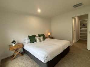 A bedroom with a bed, bedside tables, a nightstand, a lamp, and a closet.