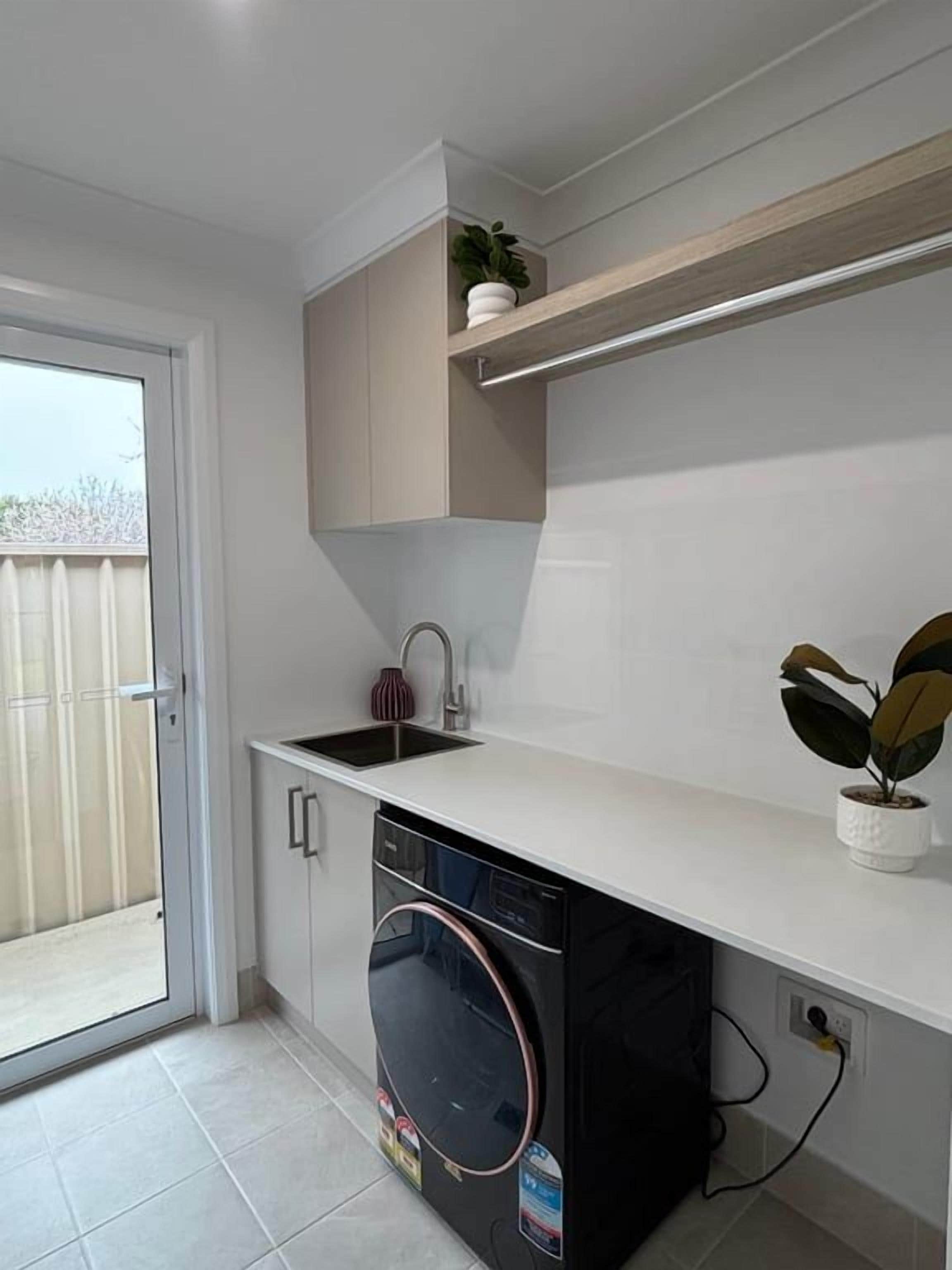 A compact kitchen with a built-in dishwasher, a sink, and a small countertop shelf.