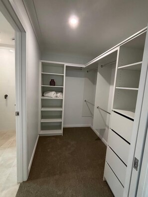 A walk-in closet with open shelving, a hanging rod, and a carpeted floor.