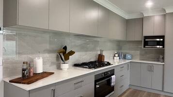 A modern kitchen with grey cabinets, a stainless steel microwave, and a wooden countertop.