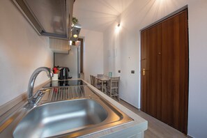 Une cuisine moderne dotée d’un évier en acier inoxydable, d’une machine à café et d’un coin repas avec une table et des chaises.
