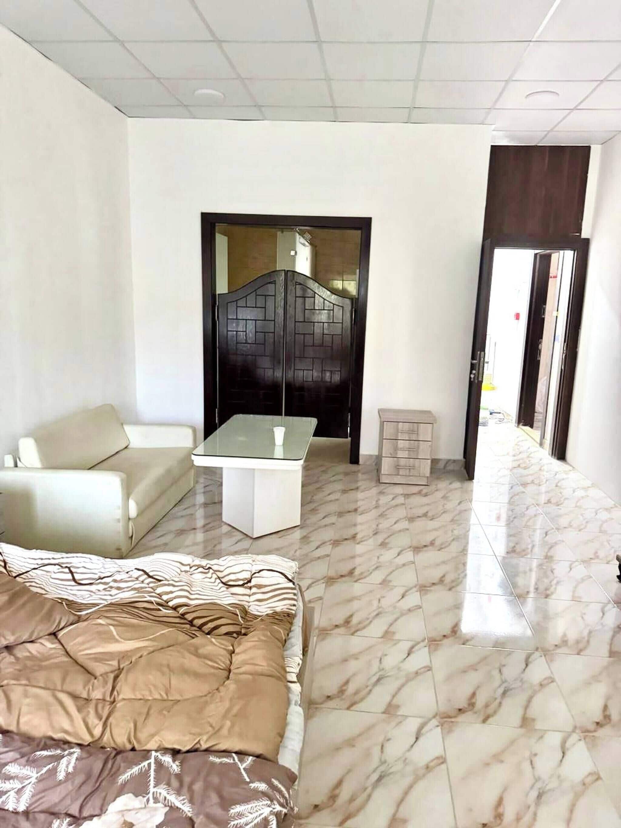 Une chambre d’hôtel avec un lit, un canap é, une petite table et une salle de bain visible à travers une porte.
