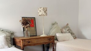 Ein Schlafzimmer mit zwei Betten, einem Nachttisch aus Holz mit einer Lampe, einem gerahmten Bild und dekorativen Kissen.