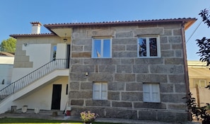 Un bâtiment en pierre de deux étages, doté d’un escalier, d’un balcon et d’un petit jardin.