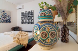 Une pièce comprenant un lit, un vase décoratif, une œuvre d’art murale et un miroir.