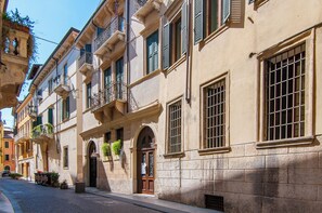 Una vista di una strada con un edificio con diverse finestre, balconi e strada acciottolata.