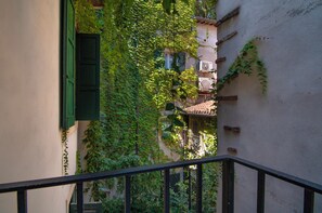 A narrow alley with buildings on either side, one with a green door and the other with a white wall partially covered in ivy. - Kedimore - Il Cuscino di Giulietta 2 (Verona)