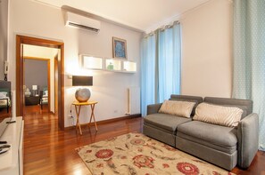 A living room with a grey sofa, patterned rug, and a small table with a lamp. - Kedimore - Il Cuscino di Giulietta 2 (Verona)