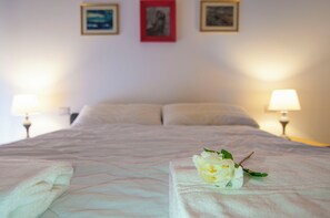 Un lit bien fait, avec des oreillers, une lampe de chevet et une fleur posée sur le couvre-lit.