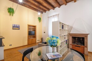 A living room with a glass table, a fireplace, a bookshelf, and a television. - Kedimore - RomeoHouse (Verona)