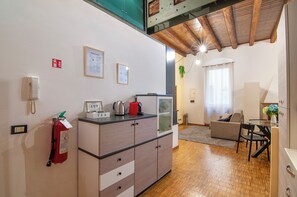 A compact living space with a kitchenette, a dining area, and a seating area with a sofa and a table. - Kedimore - RomeoHouse (Verona)