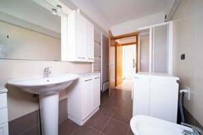 Ein modernes Badezimmer mit Waschbecken, Spiegel, Schränken und einer Duschkabine.