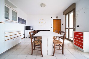 A dining area with a white table, wooden chairs, and a clock on the wall. - Kedimore - SoniaHouse (Oppeano)