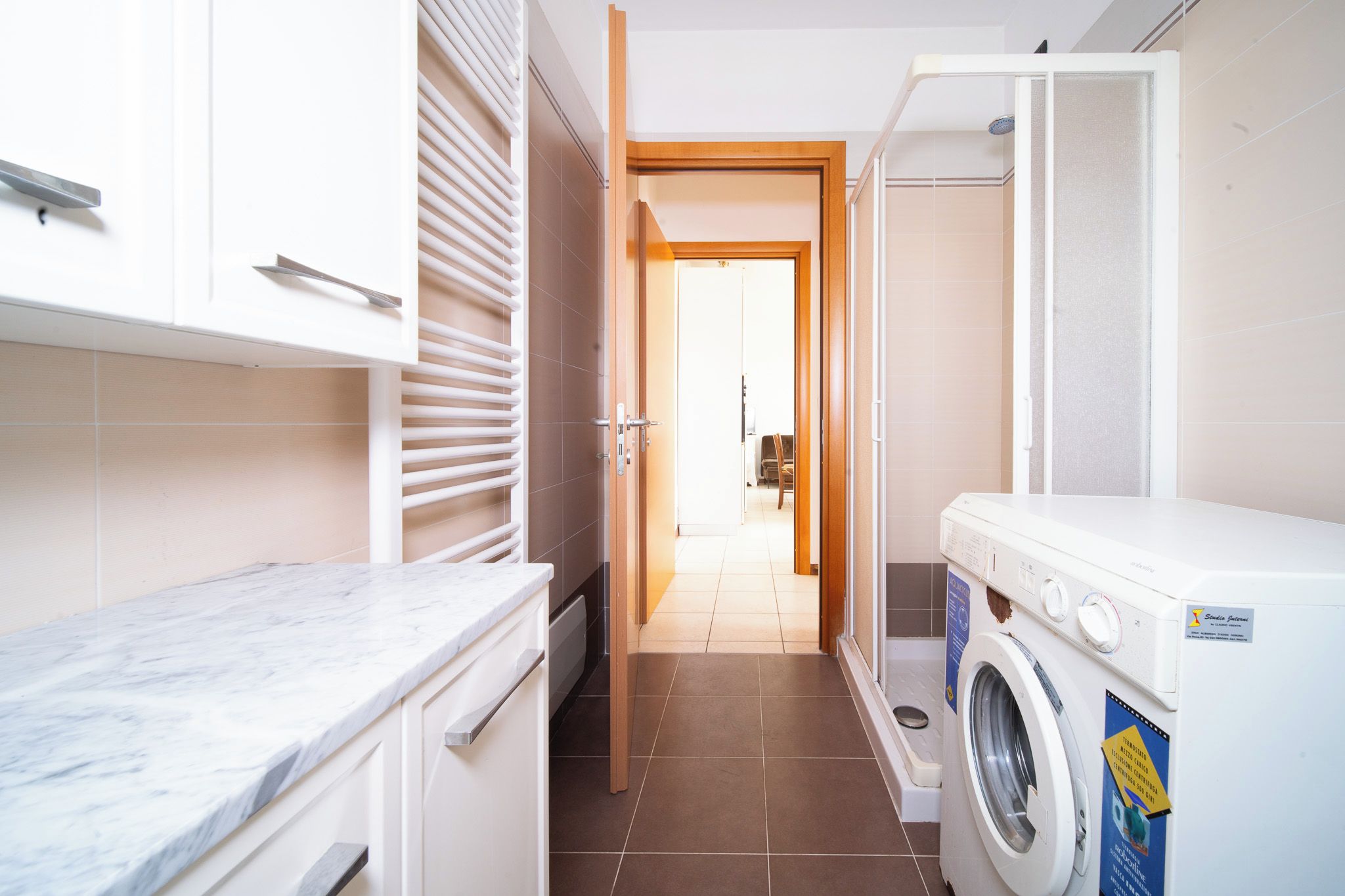 A laundry room with a washing machine, a drying rack, and a countertop.