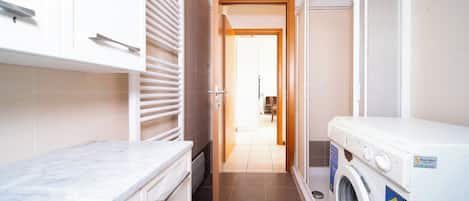 A laundry room with a washing machine, a drying rack, and a countertop.