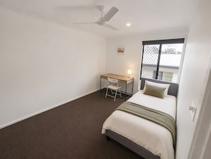 A bedroom with a bed, a desk, a chair, a ceiling fan, and a window with a view. - Private 3-Bedroom Upper-Level Apartment, Self Check-in (Collingwood Park)