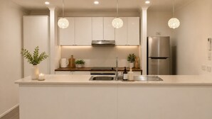 Een moderne keuken met een centraal eiland, roestvrijstalen apparatuur, hangende lampen en een strak, minimalistisch design.