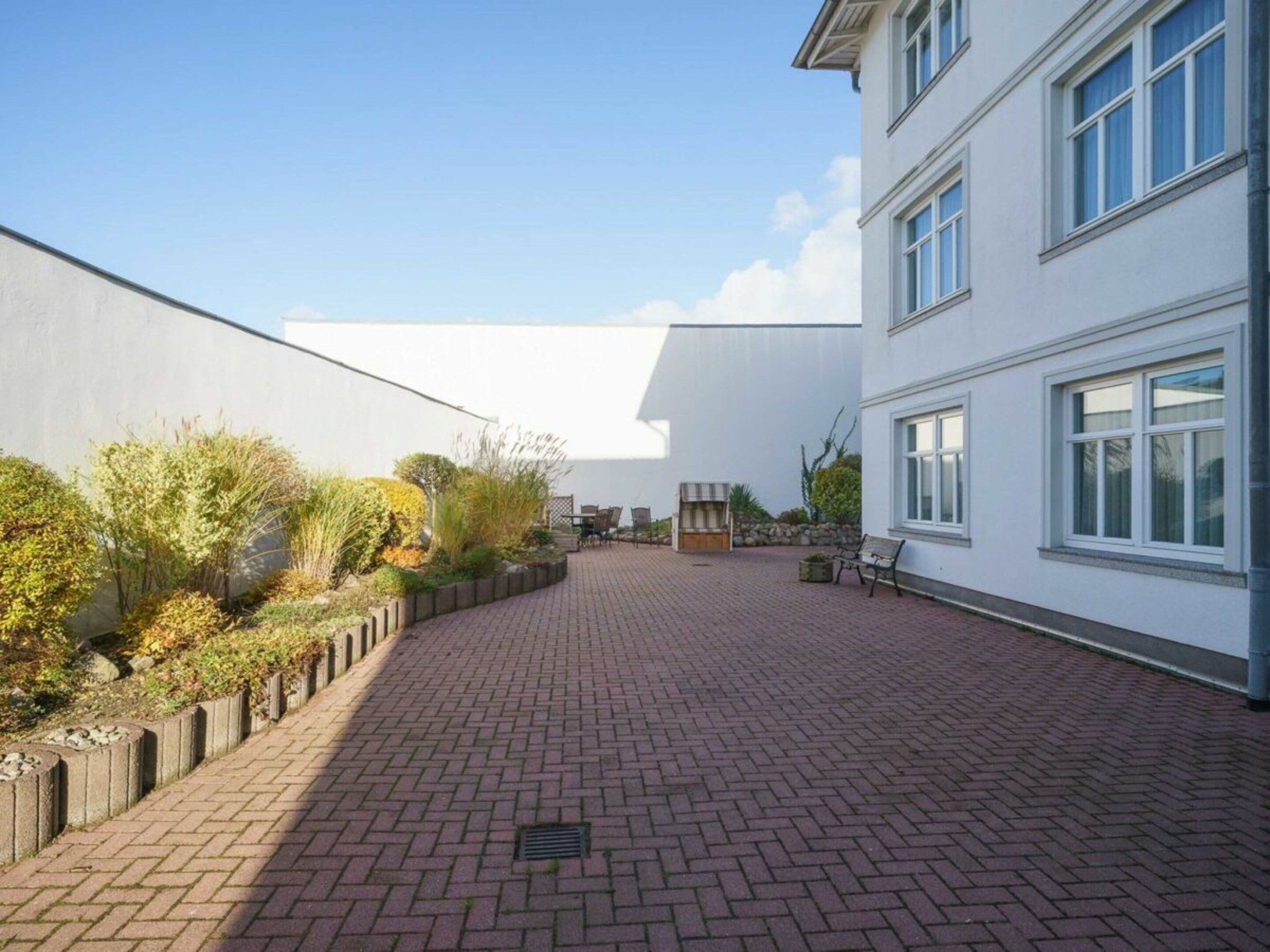 A courtyard with a brick pathway, a bench, and a small outdoor seating area.