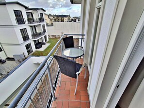 A balcony with a table and chairs, a view of neighboring buildings, and a tiled floor. - House by the spa Park (Heringsdorf)