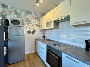 Cozinha moderna com geladeira, forno e micro-ondas.