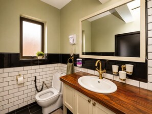 Un baño con un inodoro blanco, un espejo grande, un tocador de madera y un salpicadero con azulejos blanco y negro.