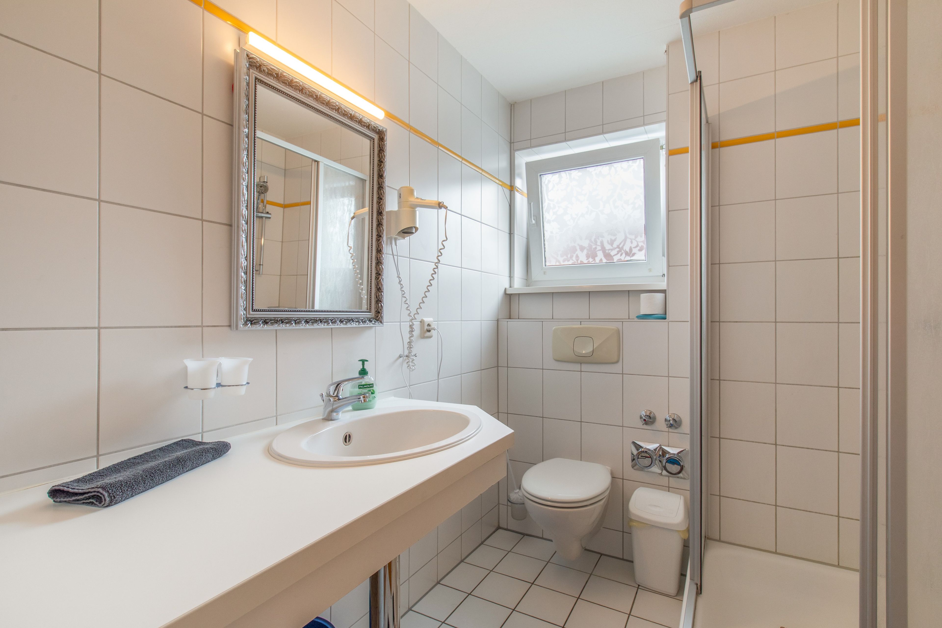 Ein Badezimmer mit Waschbecken, Spiegel, Toilette und Duschbereich.