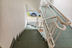 A staircase with a handrail, leading to a landing with a car parked outside.