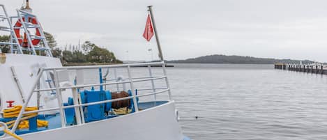A boat docked at a pier with a lifebuoy and a red flag on the deck.