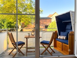 Varanda com mesa, duas cadeiras, um candeeiro e um assento almofadado azul.