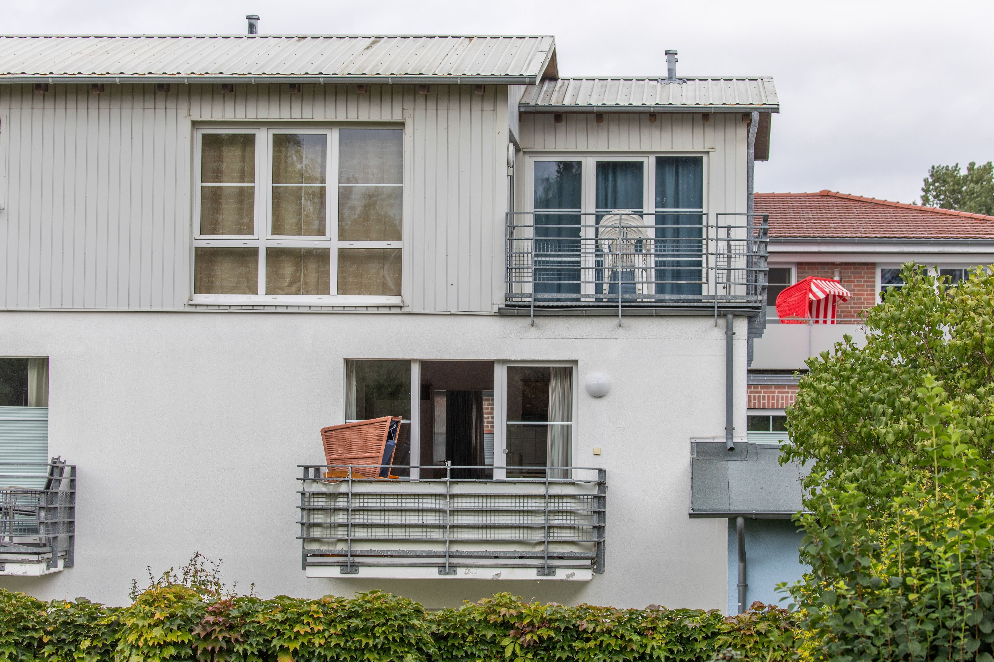 A two-story building with a balcony, a window with a metal grill, and a door.