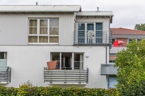 A two-story building with a balcony, a window with a metal grill, and a door.