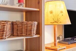 A wooden shelf with wicker baskets and a lamp with a floral lampshade.