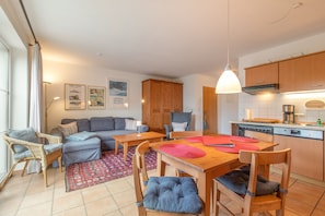 A modern kitchen with wooden cabinets, a built-in stove, and a dining area with a wooden table and chairs. - Apartment 'Hafenbrise' with Sea View, Balcony, Dogs Welcome (Putbus)