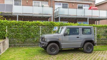 En grå SUV står parkerad på en uppfart med en byggnad i tegel som syns i bakgrunden.