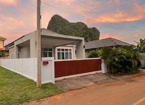 A modern house with a covered porch, a white fence, and a red gate. - Natural Pool Villa Ao nang (Mueang Krabi)