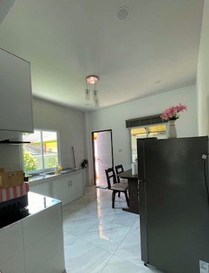 A spacious kitchen with a dining area, a refrigerator, and a window with a view.