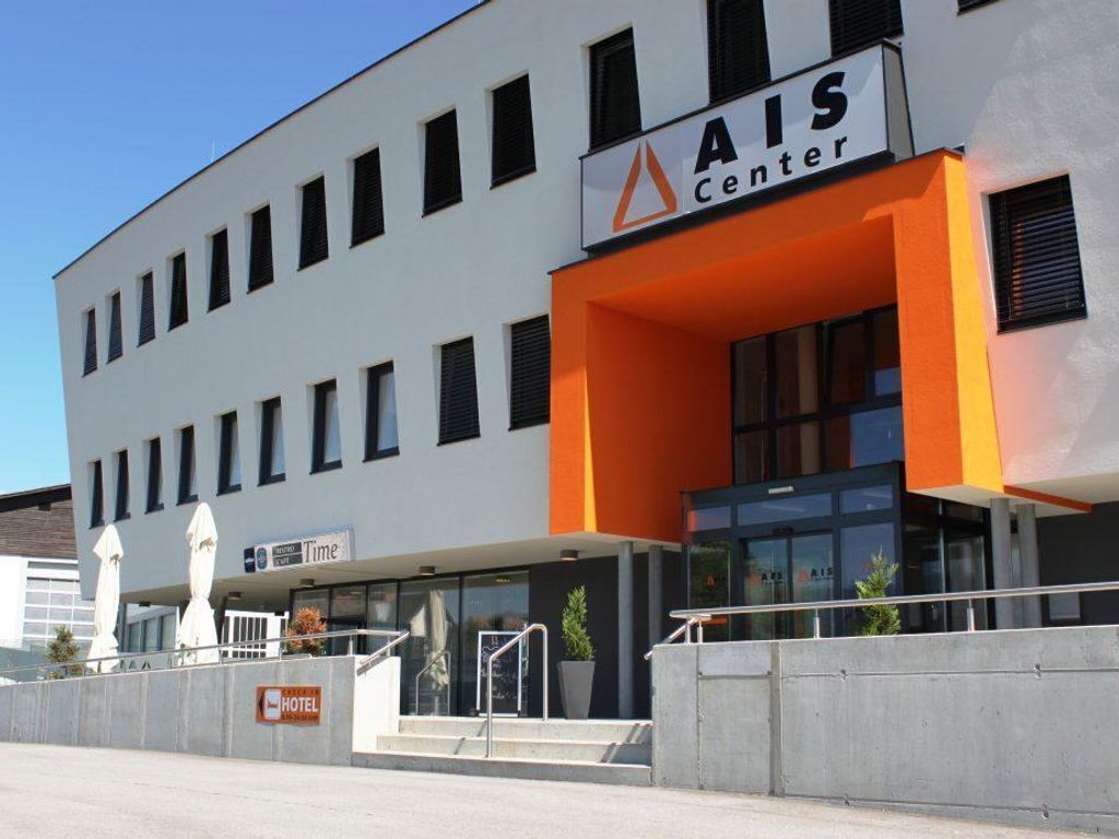 Ein modernes Gebäude mit einem Schild, auf dem 'AIS Center' steht, und einem 'HOTEL'-Schild darunter.