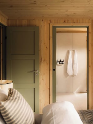 Una habitación con puerta de madera, una cama con almohada a rayas y una toalla colgada en la pared.
