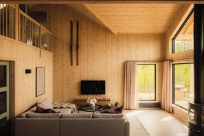 A cozy living room with a wooden interior, a flat-screen TV, a sofa, and a fireplace.
