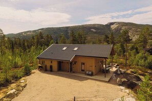 A wooden cabin with a sloped roof, a covered porch, and a gravel driveway.