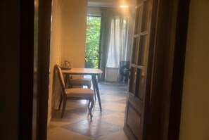 A hallway leading to a dining area with a table and chairs, a basket, and a view of greenery outside. - 2-Bedroom Apartment in Tranquil Tbilisi Perfect for Relaxing Stays (T'bilisi)