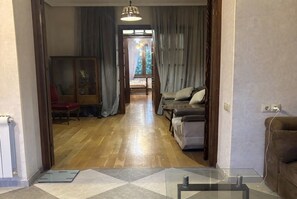 A living room with a sofa, a glass coffee table, and a wooden floor. - 2-Bedroom Apartment in Tranquil Tbilisi Perfect for Relaxing Stays (T'bilisi)