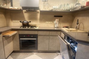 A modern kitchen with a gas stove, oven, and dishwasher. - 2-Bedroom Apartment in Tranquil Tbilisi Perfect for Relaxing Stays (T'bilisi)