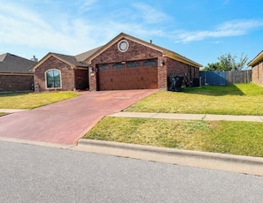 A residential property with a brick garage, a red driveway, and a well-maintained lawn. - Spacious 4 bedrooms with 5 beds house very close to Food hood (Killeen)