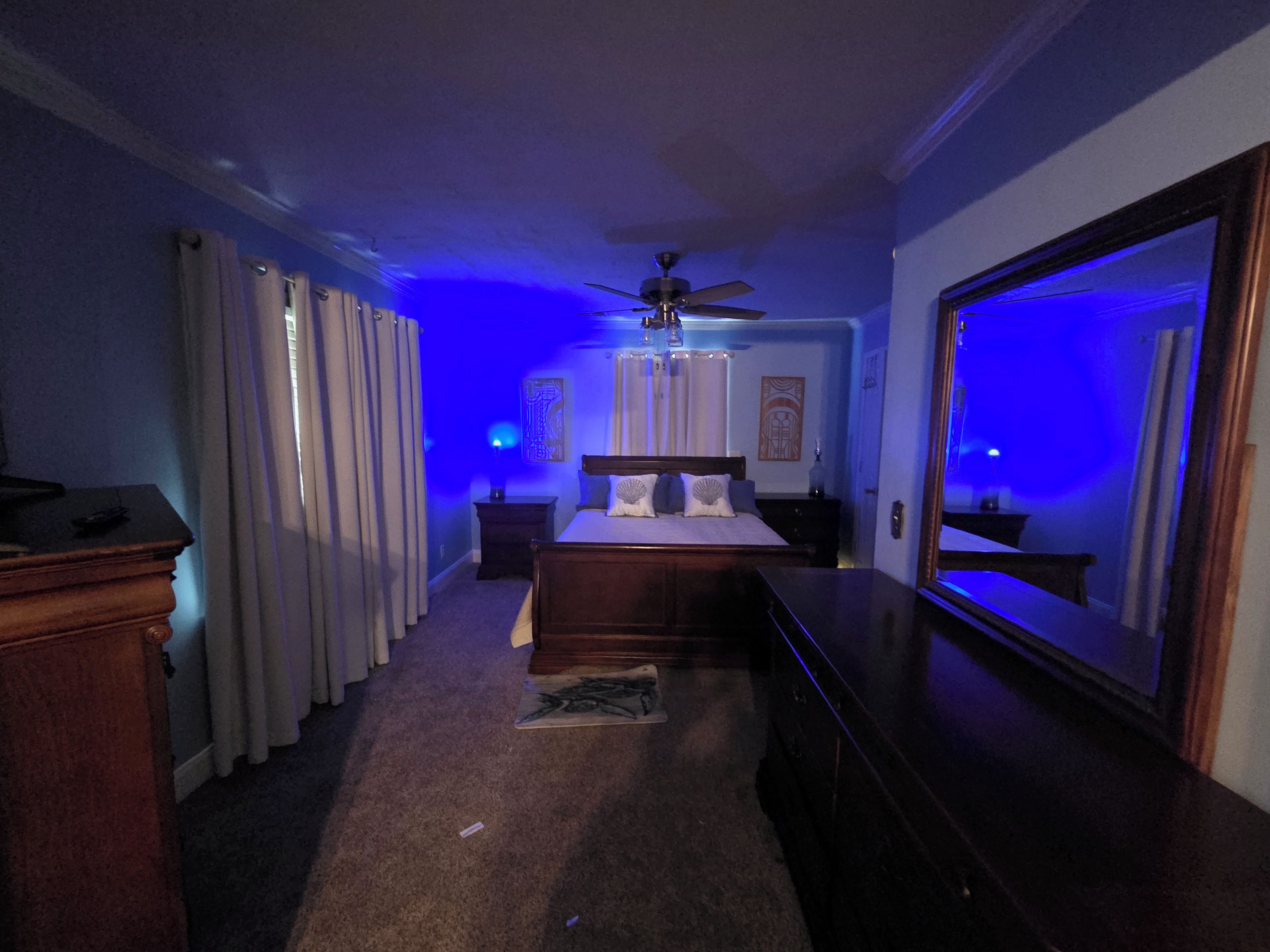 Une chambre à coucher avec un lit, un ventilateur de plafond, une commode et un miroir.