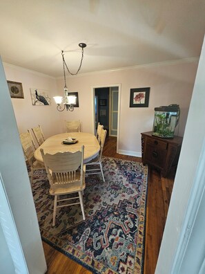 A dining area with a round table, chairs, a chandelier, and a fish tank. - The Palmetto Oasis Poolside Retreat (Cayce)