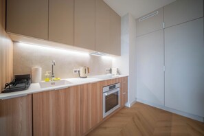 Cuina moderna amb armaris de fusta, forn integrat i taulell blanc.