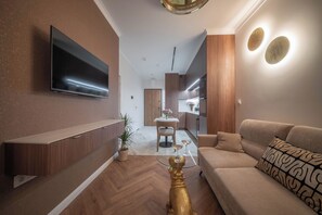 A modern living room with a flat-screen TV, a sofa, a coffee table, and a dining area with a table and chairs. - Chmielna Duo Exclusive | Warsaw Center & Parking (Warszawa)
