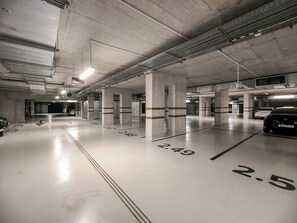 Eine mehrgeschossige Parkgarage mit Betonpfeilern, deutlichen Richtungsweisern und nummerierten Parkplätzen.